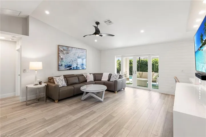 Living area featuring vaulted ceiling, light wood finished floors, recessed lighting, ceiling fan, and french doors