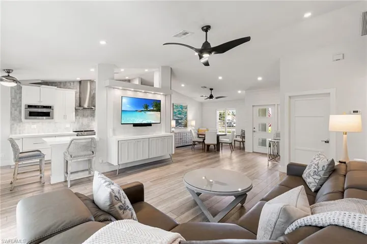 Living area with a ceiling fan, lofted ceiling, light wood-type flooring, and recessed lighting