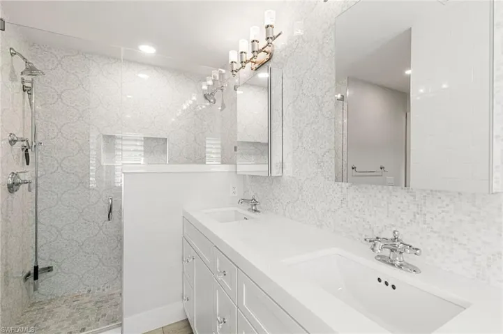 Bathroom with double vanity, a stall shower, and tasteful backsplash