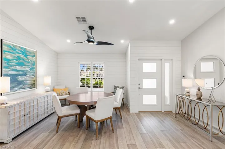 Dining area featuring vaulted ceiling, light wood-style flooring, recessed lighting, wood walls, and a ceiling fan