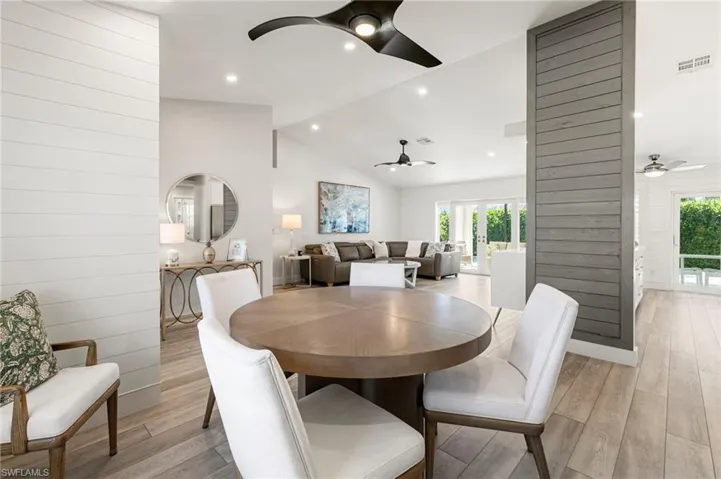 Dining room with wooden walls, lofted ceiling, plenty of natural light, light wood-style flooring, and recessed lighting