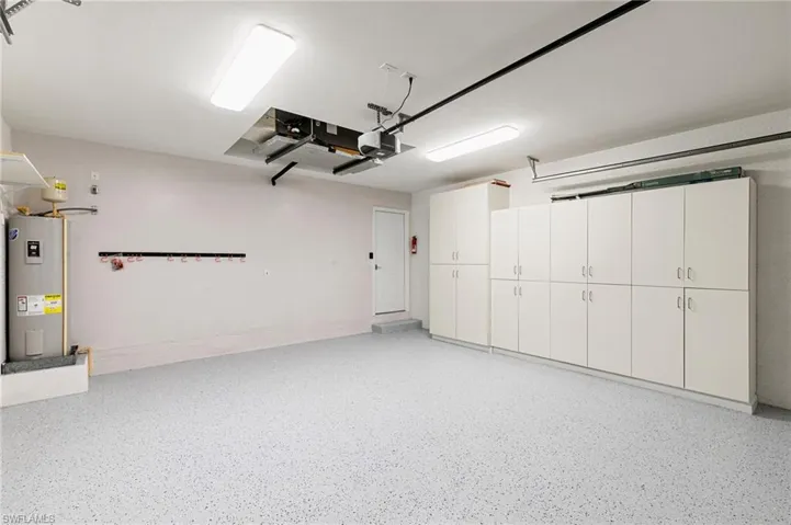 Garage featuring electric water heater and a garage door opener