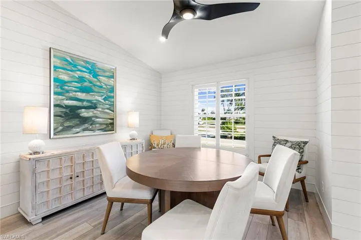 Dining space featuring wooden walls, wood finished floors, vaulted ceiling, and a ceiling fan