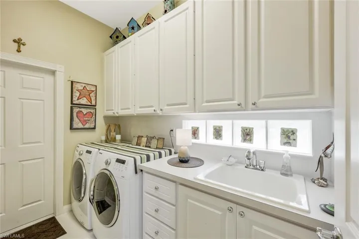 Clothes washing area featuring sink, cabinets, and separate washer and dryer