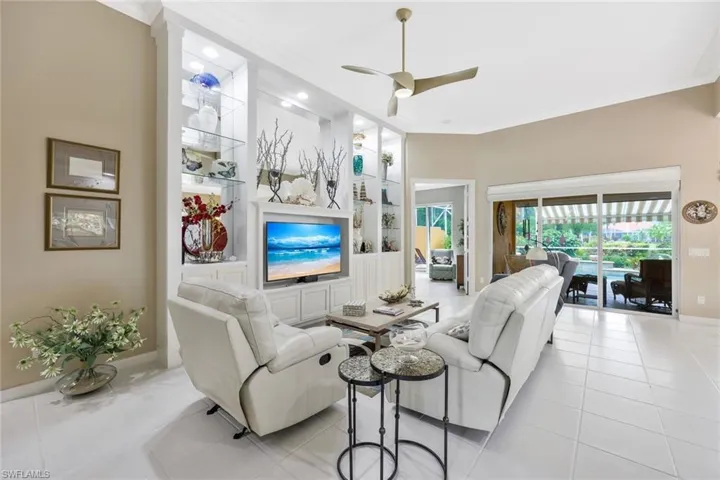 Tiled living room with ceiling fan and crown molding