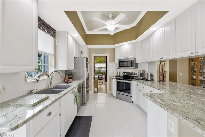 Kitchen featuring white cabinets, appliances with stainless steel finishes, ceiling fan, and light tile floors