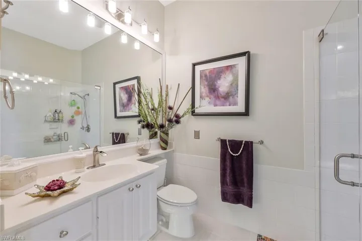 Bathroom featuring tile walls, toilet, tile floors, an enclosed shower, and vanity