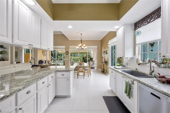 Kitchen with dishwasher, pendant lighting, light tile floors, sink, and white cabinetry