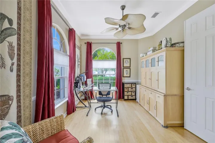 Home office with light hardwood / wood-style floors, ornamental molding, and ceiling fan