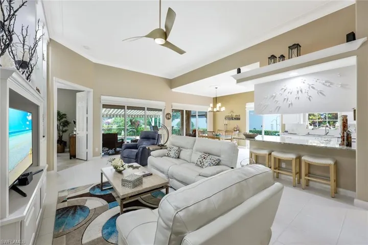 Tiled living room with ornamental molding and ceiling fan with notable chandelier