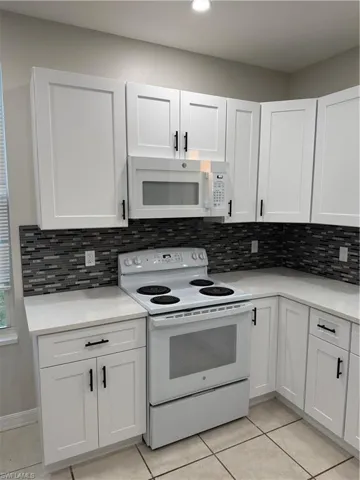 Kitchen featuring healthy amount of natural light, white appliances, and white cabinets