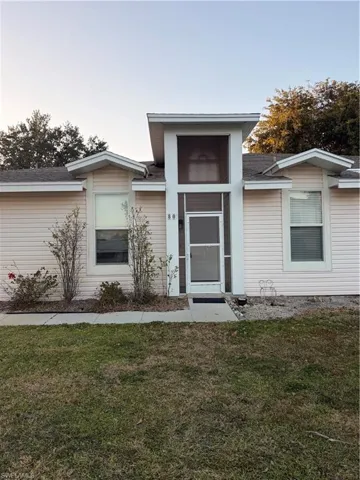 Doorway to property featuring a yard and roof with shingles