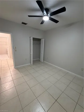 Unfurnished bedroom with a closet, light tile patterned floors, and ceiling fan