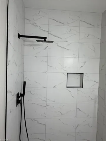Bathroom with vanity, a tile shower, and light tile patterned flooring