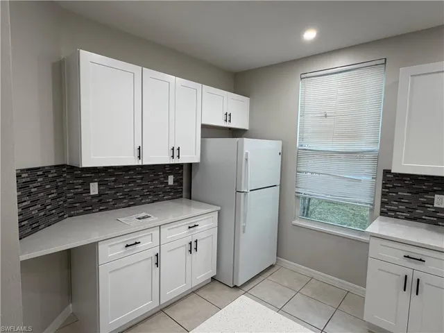 Kitchen featuring backsplash, white appliances, light stone counters, white cabinetry, and recessed lighting