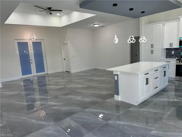 Kitchen featuring stainless steel stove, dark tile patterned flooring, ceiling fan, a raised ceiling, and white cabinets