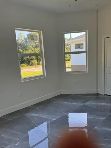 Empty room featuring plenty of natural light and dark tile patterned floors