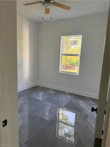 Tiled spare room featuring ceiling fan