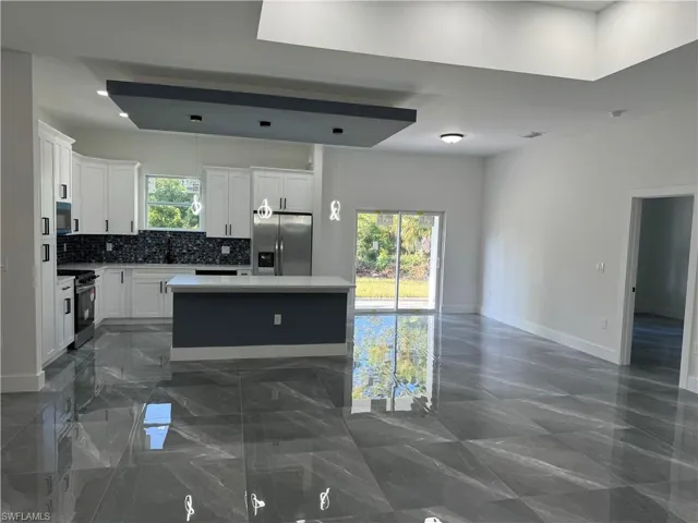 Kitchen with a center island, white cabinetry, appliances with stainless steel finishes, and a healthy amount of sunlight