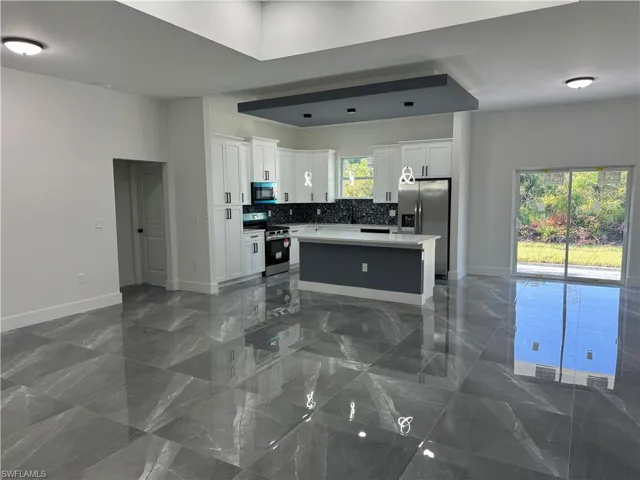 Kitchen with white cabinets, a center island, a healthy amount of sunlight, and stainless steel appliances