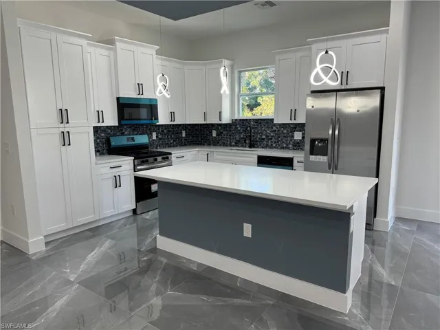 Kitchen with white cabinets, appliances with stainless steel finishes, and a kitchen island