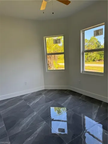 Spare room with ceiling fan and dark tile patterned floors