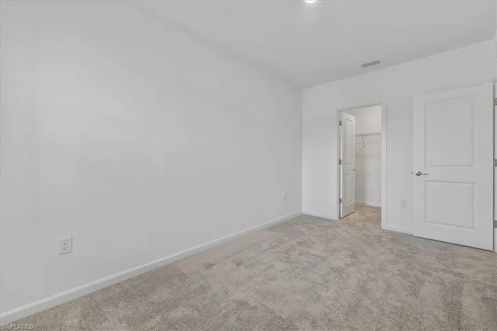 Unfurnished bedroom featuring carpet floors, baseboards, a walk in closet, and a closet