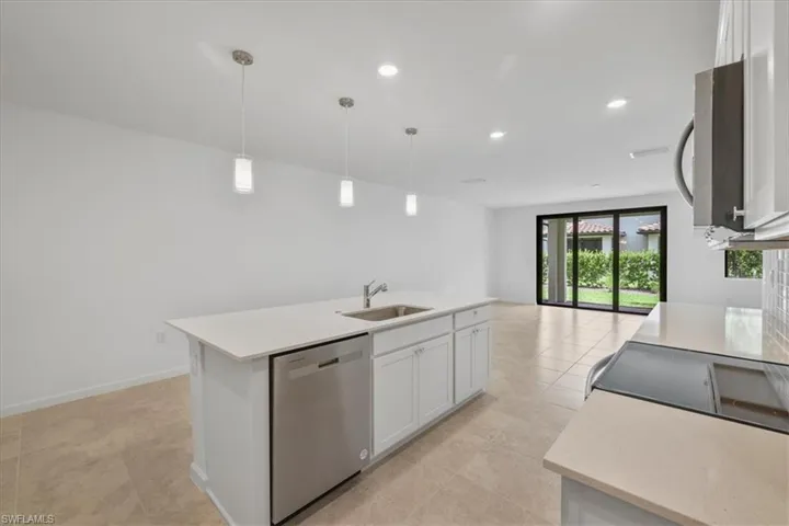 Kitchen featuring stainless steel appliances, a sink, light countertops, white cabinets, and open floor plan