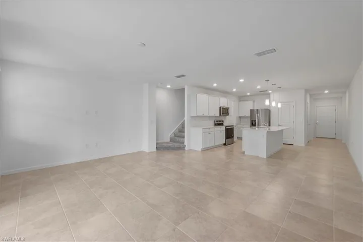 Unfurnished living room with recessed lighting, stairs, baseboards, and light tile patterned flooring
