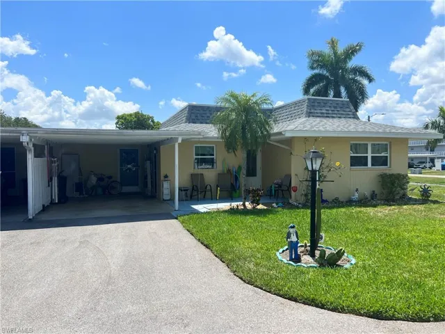View of front of property with a carport and a front lawn