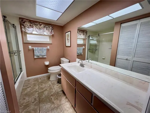 Full bathroom featuring vanity, enclosed tub / shower combo, and toilet
