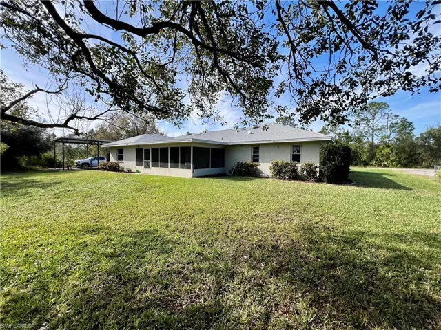 Rear view of house with a sunroom and a lawn