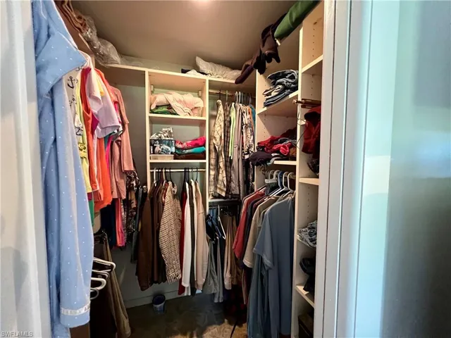 Walk in closet with built  in California Closet shelving and drawers.