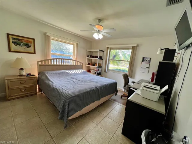 Bedroom with ceiling fan, light tile patterned flooring, and multiple windows
