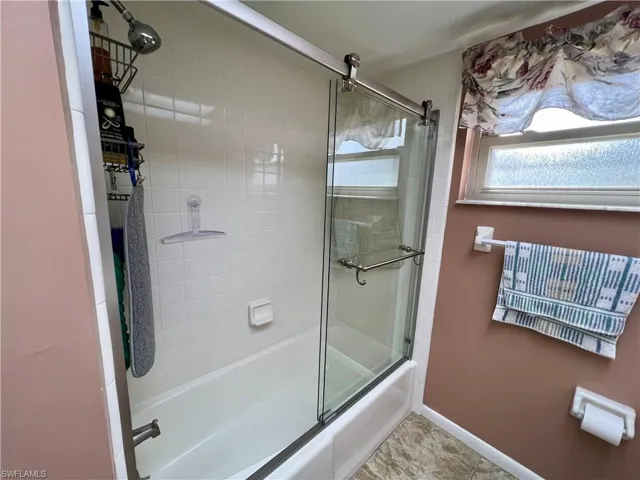 Bathroom featuring tile patterned floors and bath / shower combo with glass door