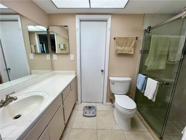 Primary Bathroom with tile patterned floors, vanity, an enclosed shower, and toilet