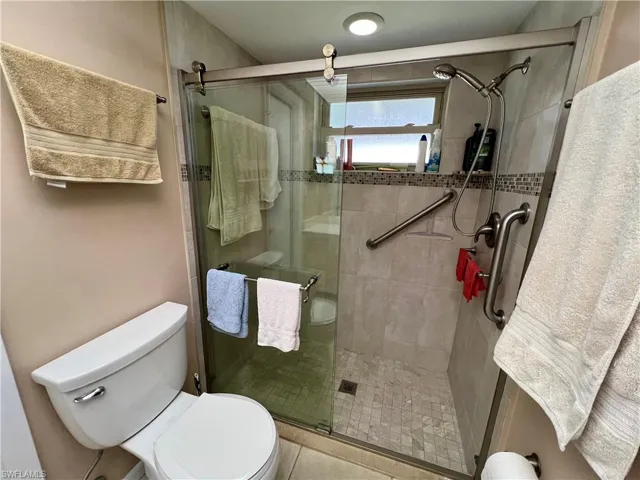 Primary Bathroom with tile patterned flooring, toilet, and an enclosed shower