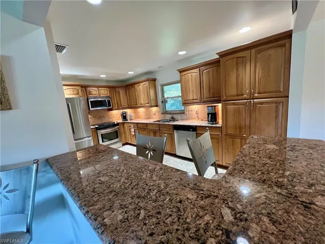 Kitchen featuring sink, GRANITE countertops, appliances with stainless steel finishes, stone tile backsplash.