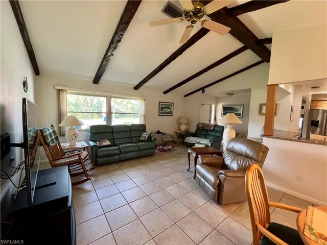 Tiled living room featuring lofted ceiling with beams and ceiling fan