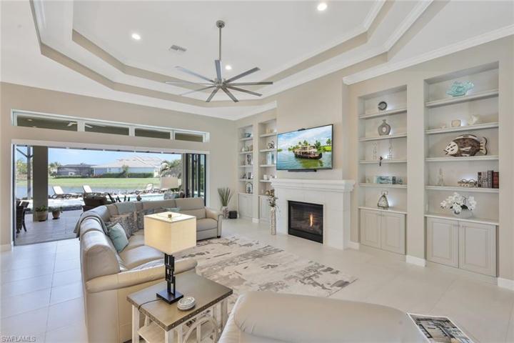 Grand Room with gas fireplace facing pool and lake area, custom cabinetry & shelves with lighting!  Faces Easterlywith Battery operated Roller Shades for Laai Sliders which pocket to the side for an open view.
