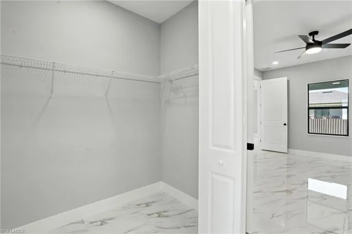 Walk in closet with marble finish flooring and ceiling fan