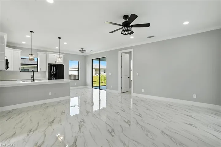 Kitchen with black fridge with ice dispenser, open floor plan, crown molding, light countertops, and recessed lighting