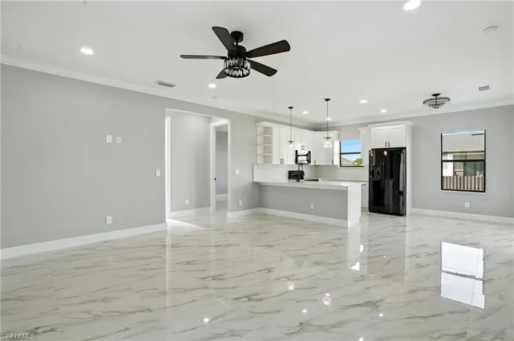 Unfurnished living room featuring ceiling fan, recessed lighting, light marble finish flooring, and ornamental molding