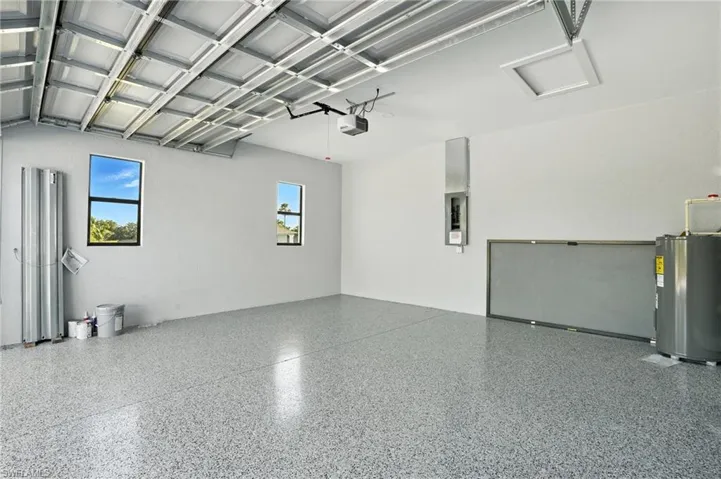 Garage with a garage door opener, electric water heater, and electric panel