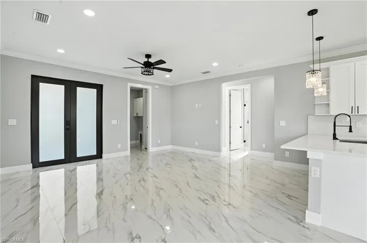 Unfurnished living room featuring recessed lighting, ceiling fan, french doors, ornamental molding, and light marble finish flooring