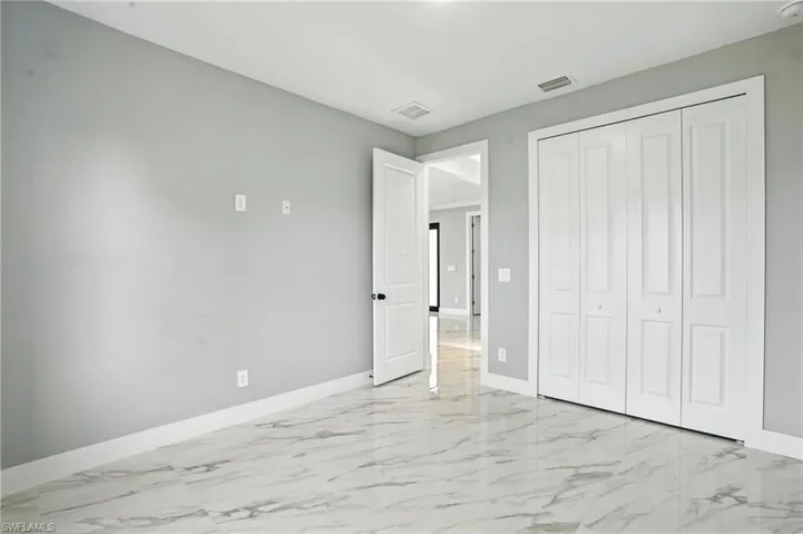 Unfurnished bedroom with light marble finish floors and a closet