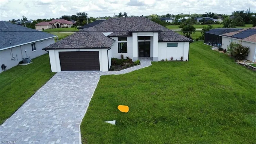 View of front of property featuring decorative driveway, stucco siding, a front lawn, and an attached garage