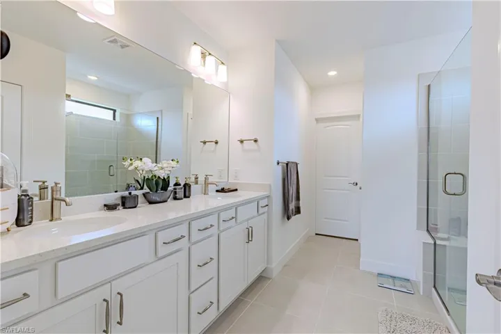 Full bath with tile patterned floors, a stall shower, and double vanity