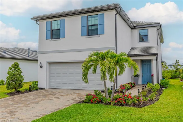 View of front of home with an attached garage, decorative driveway, stucco siding, a front lawn, and a tile roof