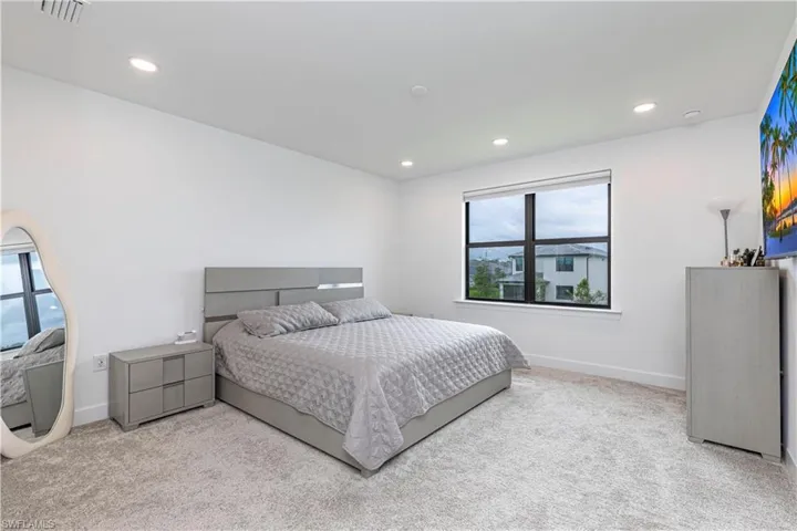 Carpeted bedroom with multiple windows, recessed lighting, and baseboards